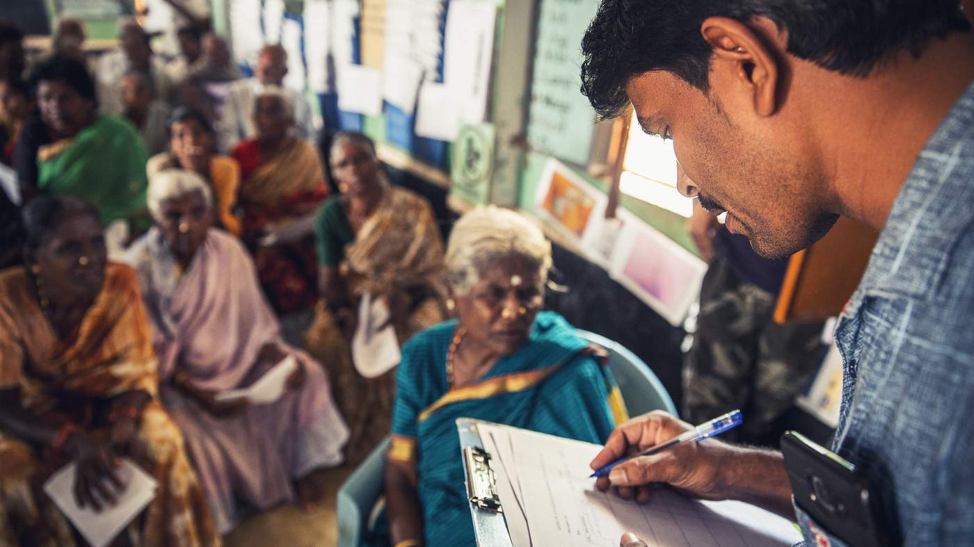 SANSCOG Volunteer Shivakumar helping villagers to fill the registration form. After the first level registration and filling consent forms, the villagers will undergo over 30 medical tests. Photo : Rajesh Subramanian